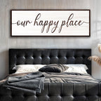 Bedroom with black tufted headboard and 'our happy place' wall art