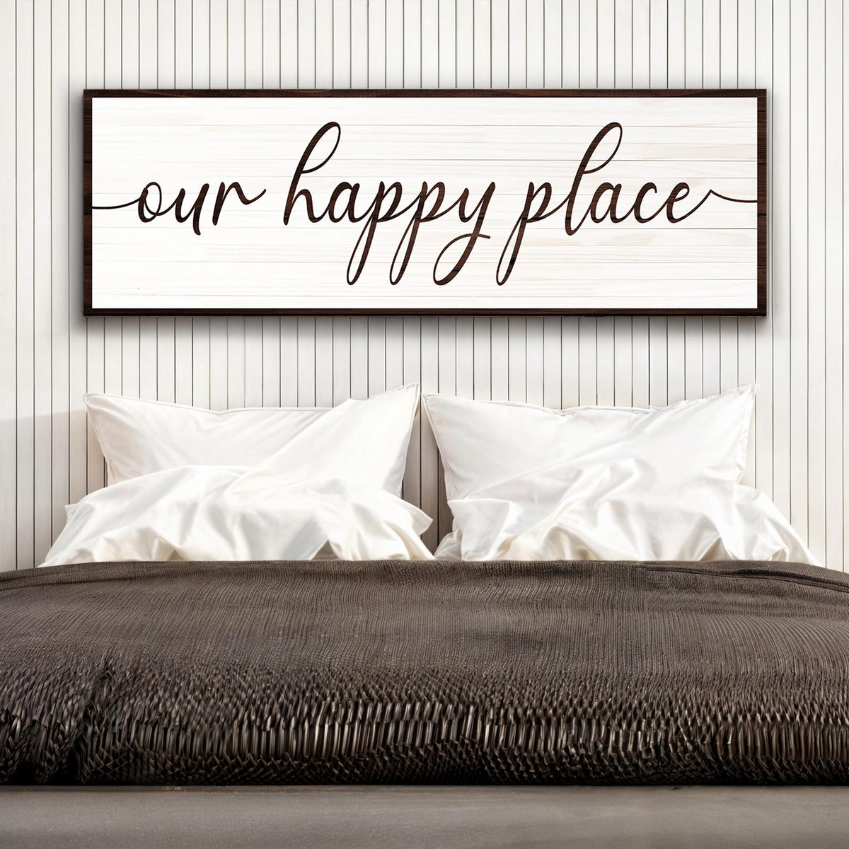 Framed artwork with 'our happy place' text above a bed in a bedroom setting.
