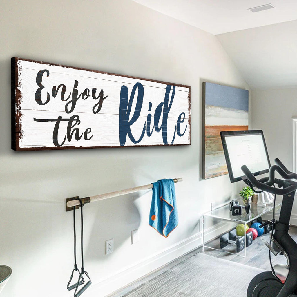 Motivational wall sign 'Enjoy the Ride' in a home setting with exercise equipment.