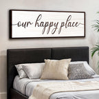 Bedroom with a large framed sign above the bed reading 'our happy place'.