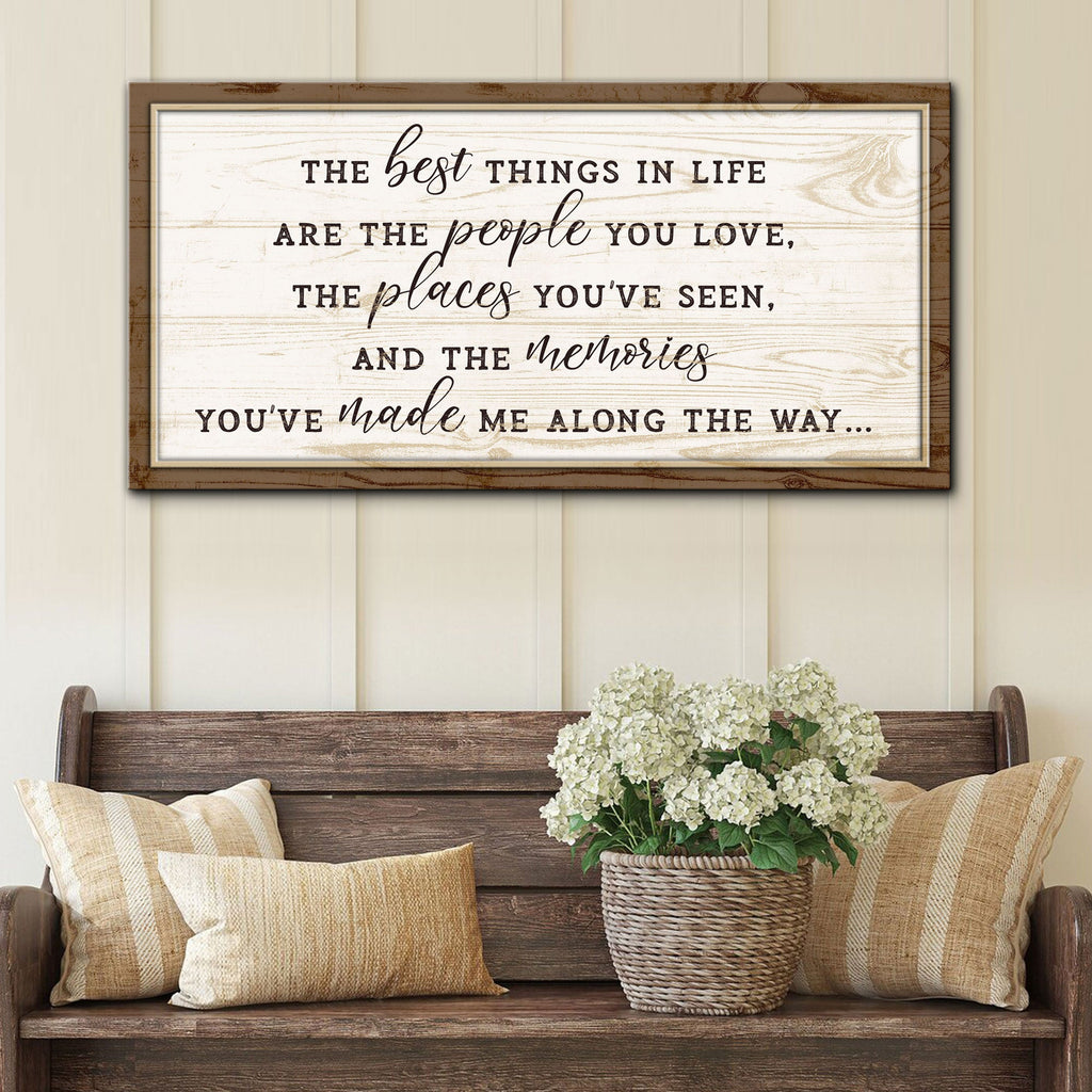 Decorative wall sign with inspirational quote above a wooden bench with pillows and a plant.