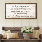 Decorative wall sign with inspirational quote above a wooden bench with pillows and a plant.