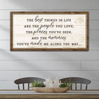 Wooden framed sign with motivational quote on a wall above a table with decor items.