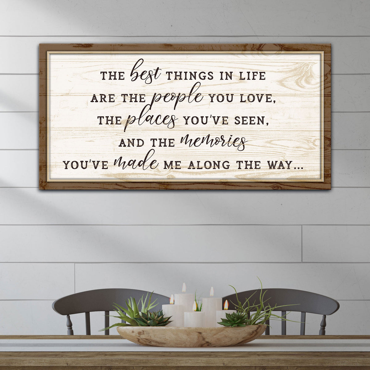 Wooden framed sign with motivational quote on a wall above a table with decor items.
