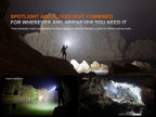 Person exploring a cave with a flashlight, surrounded by rocky landscape.
