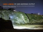Person with a flashlight on a cliffside at night, illuminating a coastal area.