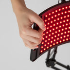 Hand holding a red LED panel against a gray background